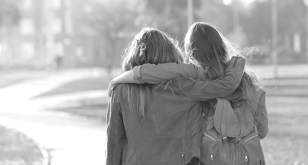 Two women with arms around each other in a supportive manner