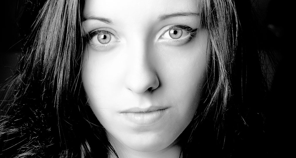 A close-up of a woman's face, looking confident while gazing directly into the camera.